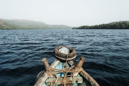 Free A tranquil landscape capturing a rustic wooden boat on a serene lake surrounded by lush hills and tranquil waters. Stock Photo