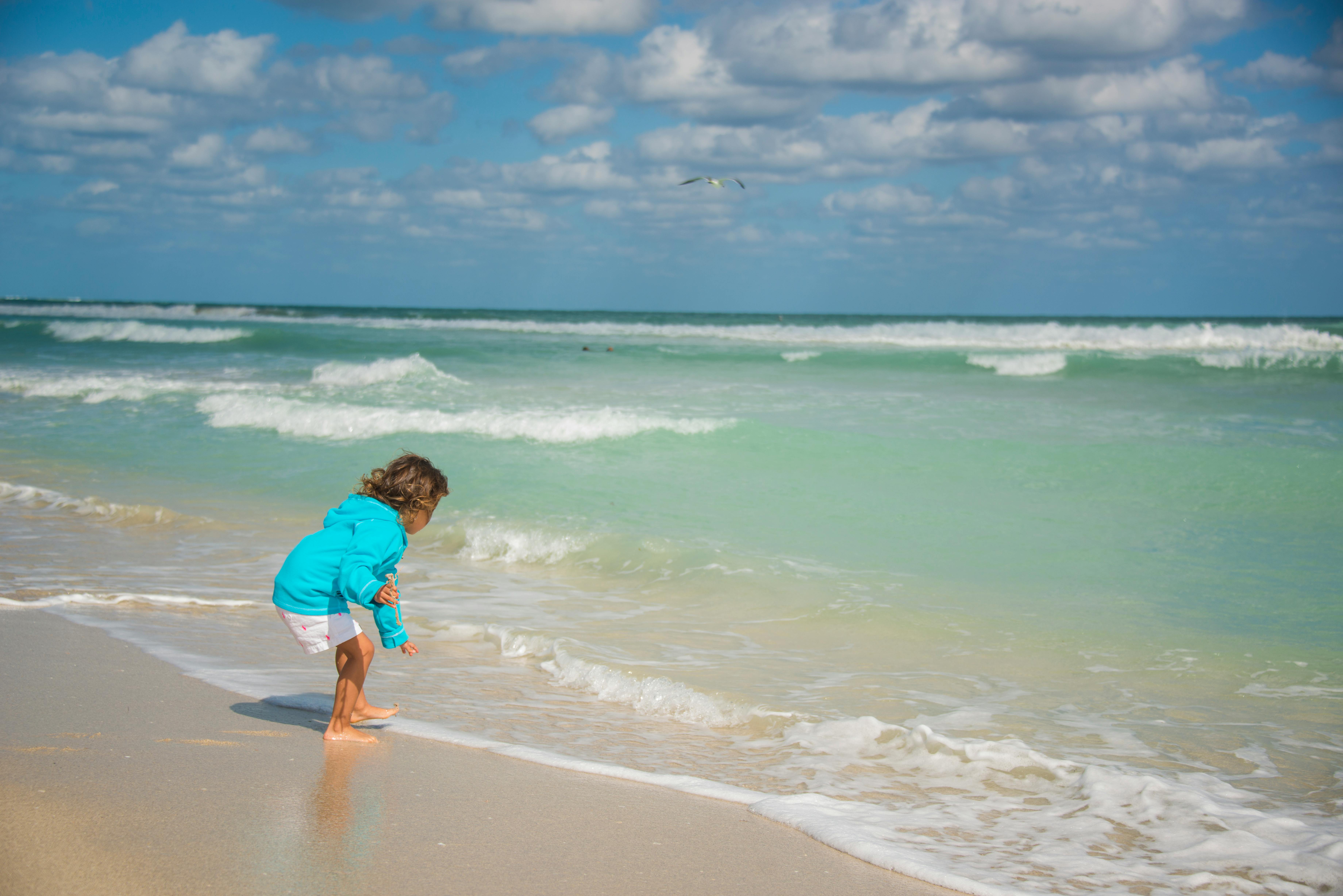 toddler playing on tropical beach with family