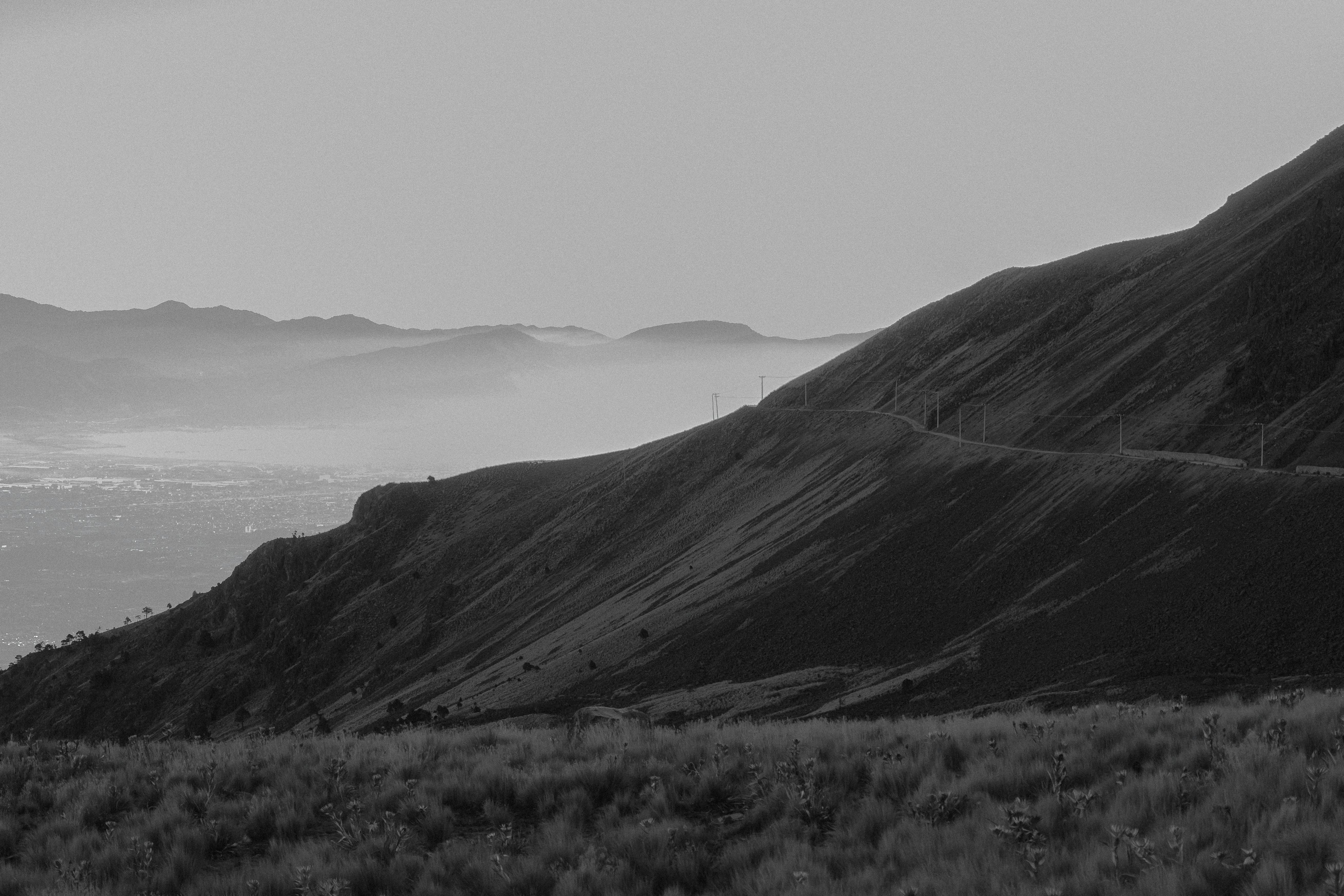 Black and white mountain landscape capturing the serene countryside with foggy hills.