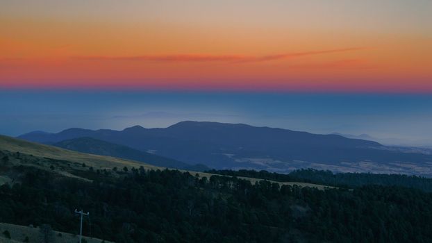 A stunning aerial view of sunset over rolling hills, capturing nature's vibrant and serene beauty.