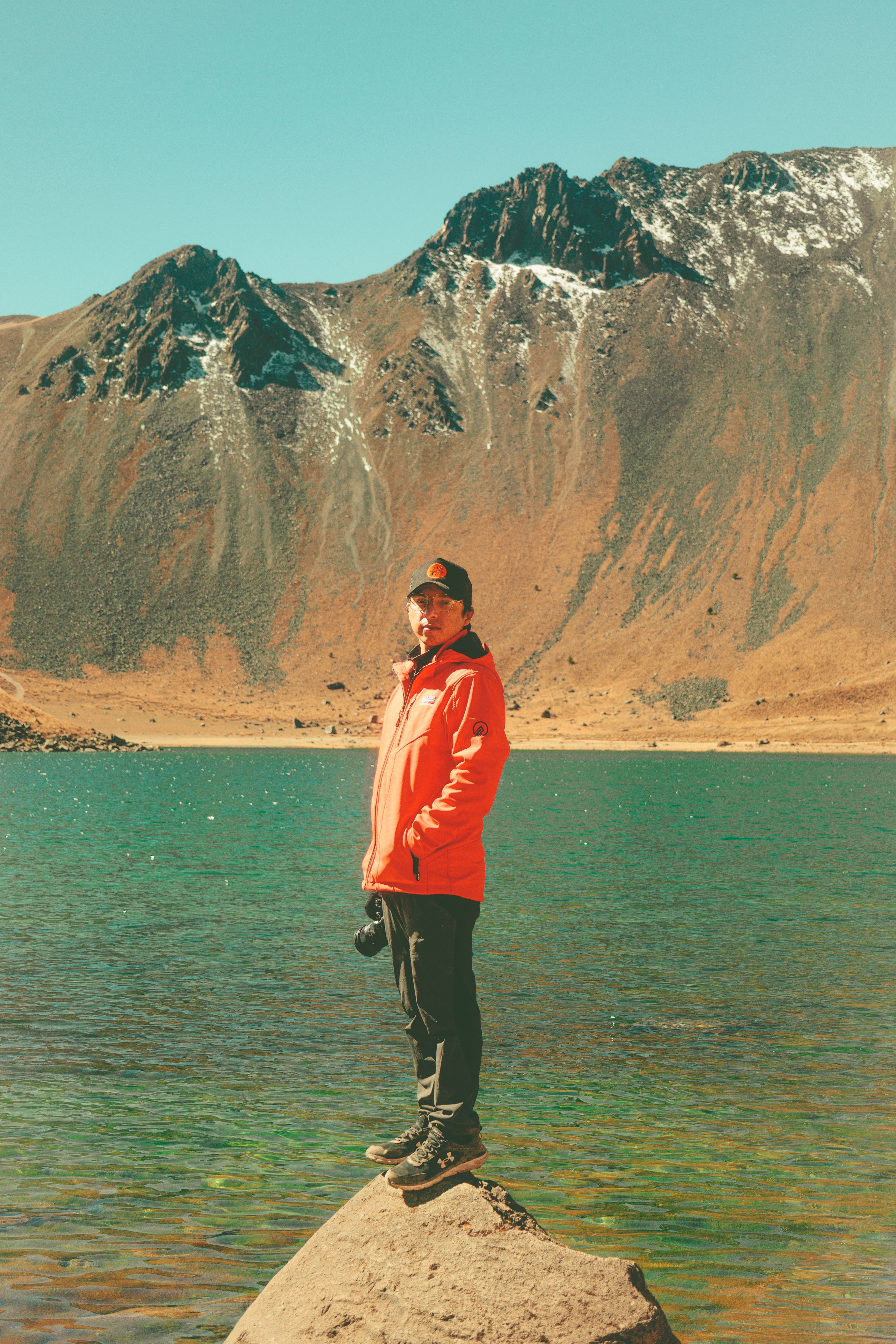 Man in Jacket Standing on Rock over Lake · Free Stock Photo