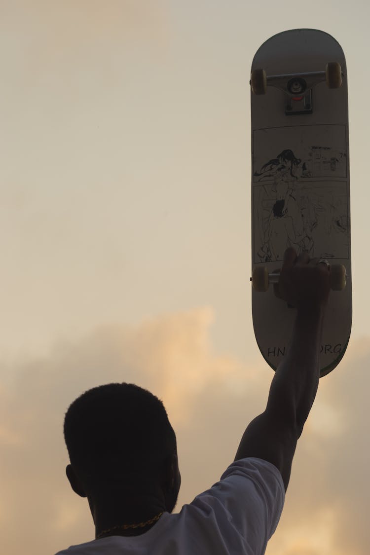 Back View Of A Man Holding A Skateboard