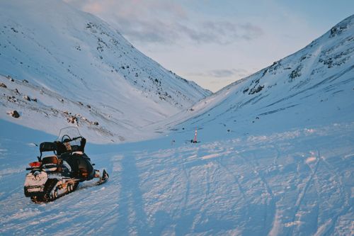 Free A snowmobile parked on a vast snow-covered mountain landscape during a serene winter day. Stock Photo