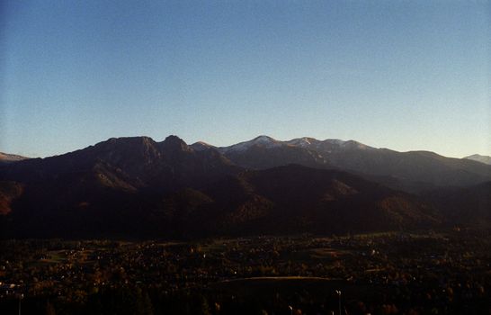 A captivating view of a mountain range at dusk overlooking a peaceful rural valley and village.