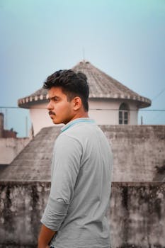 A thoughtful man standing with unique architectural structure in the background.