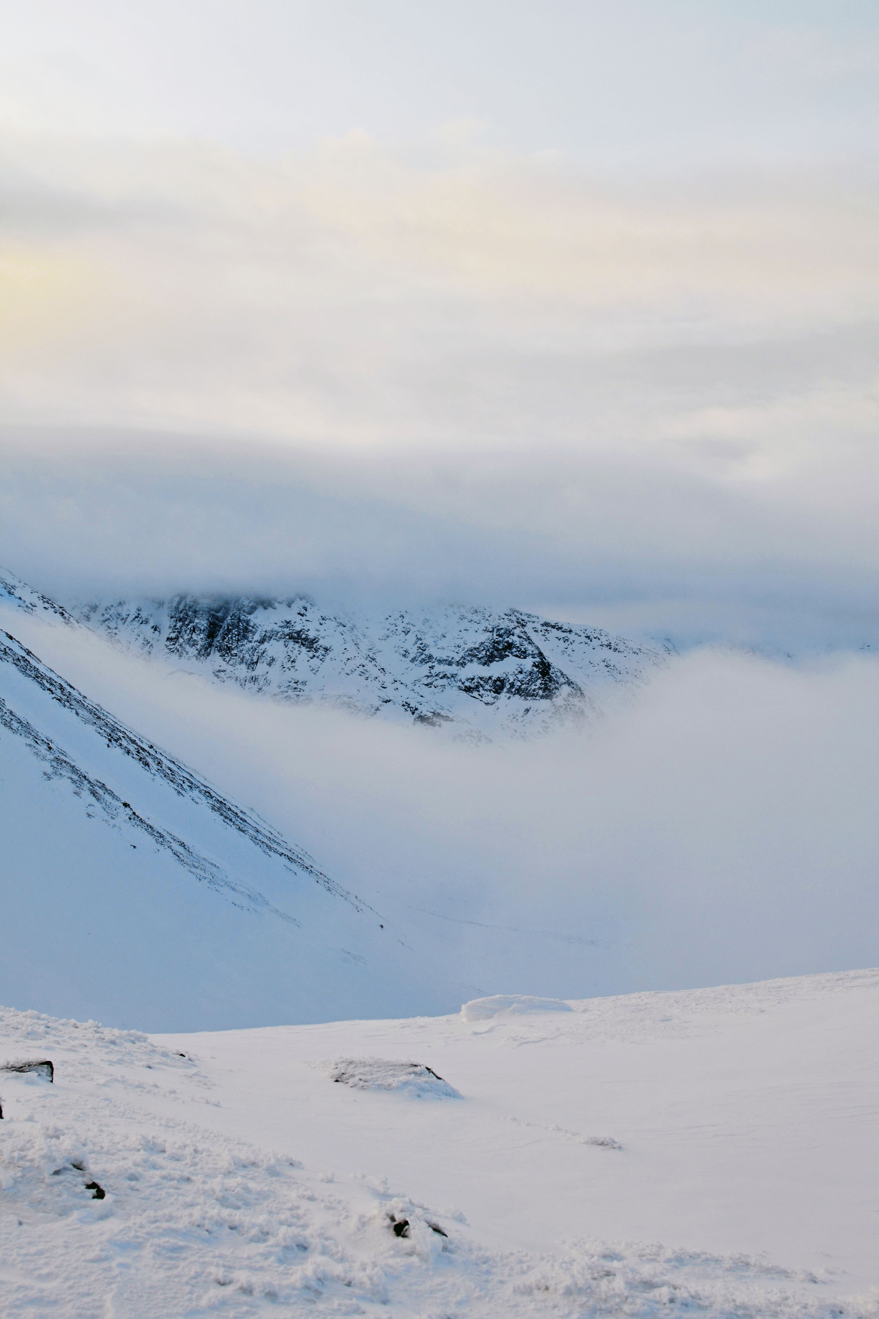Snow-covered mountain ridge wrapped in low winter cloud — photo by Darya Grey_Owl on Pexels