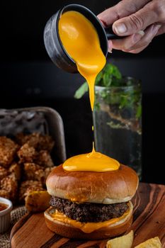 Delicious gourmet cheeseburger with cheese sauce being poured on top for a perfect fast food meal.
