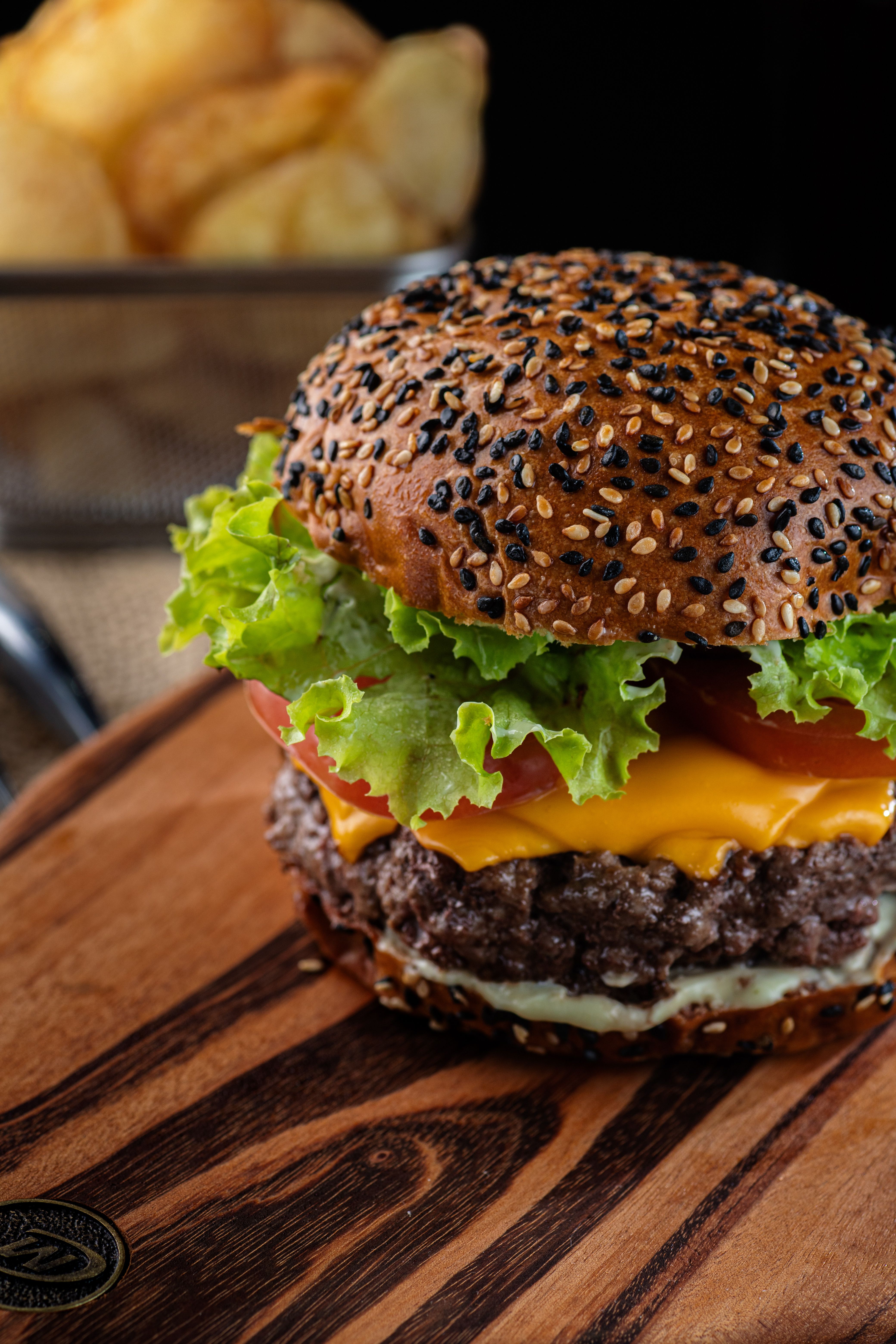Close-up of a delicious cheeseburger with fresh lettuce and tomato served on a wooden board.