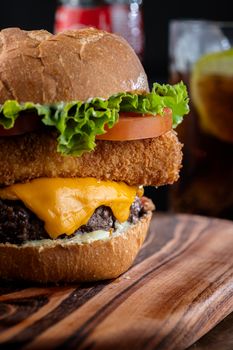 Mouthwatering gourmet cheeseburger with toppings on a wooden board, perfect for lunch.