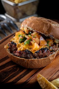 Close-up of a delicious gourmet cheeseburger with fresh toppings on a wooden board, perfect for food enthusiasts.
