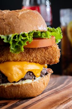 Mouthwatering burger with cheese, lettuce, tomato, and fried onion on a wooden board.