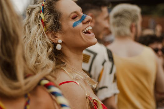 A joyful woman with vibrant festival makeup enjoys a lively outdoor street festival.