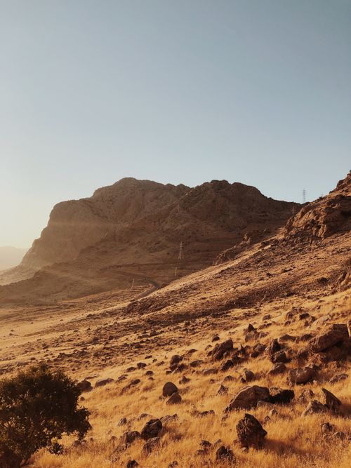 Free A scenic view of a sunlit rocky mountain landscape with sparse vegetation. Stock Photo