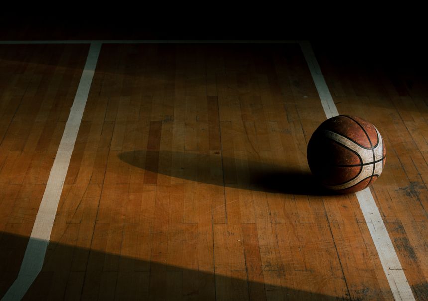 Basketball resting on a dimly lit hardwood court — Onur Bahadır on Pexels