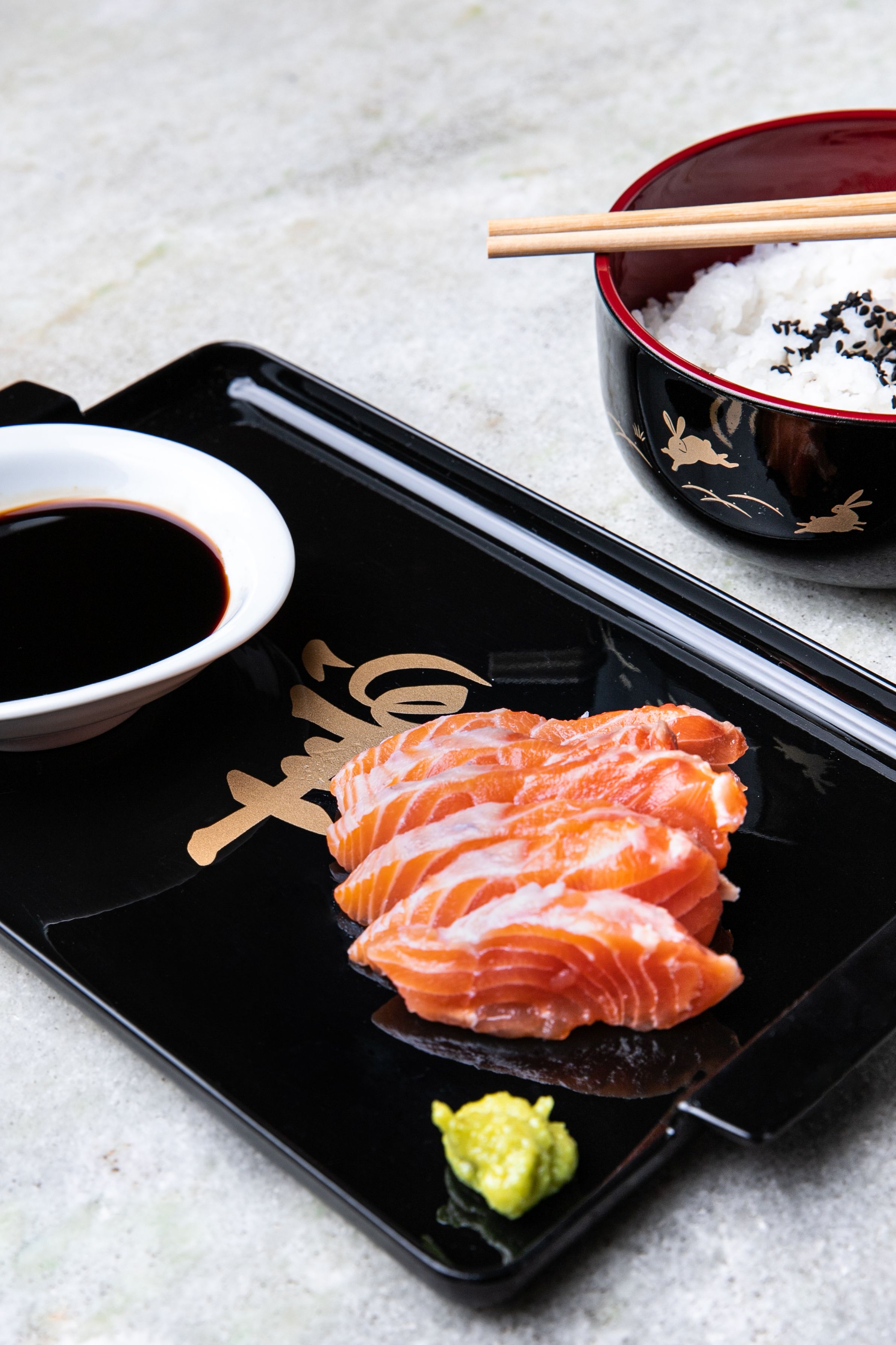 A close-up of salmon sashimi served with rice and soy sauce, showcasing Japanese cuisine.