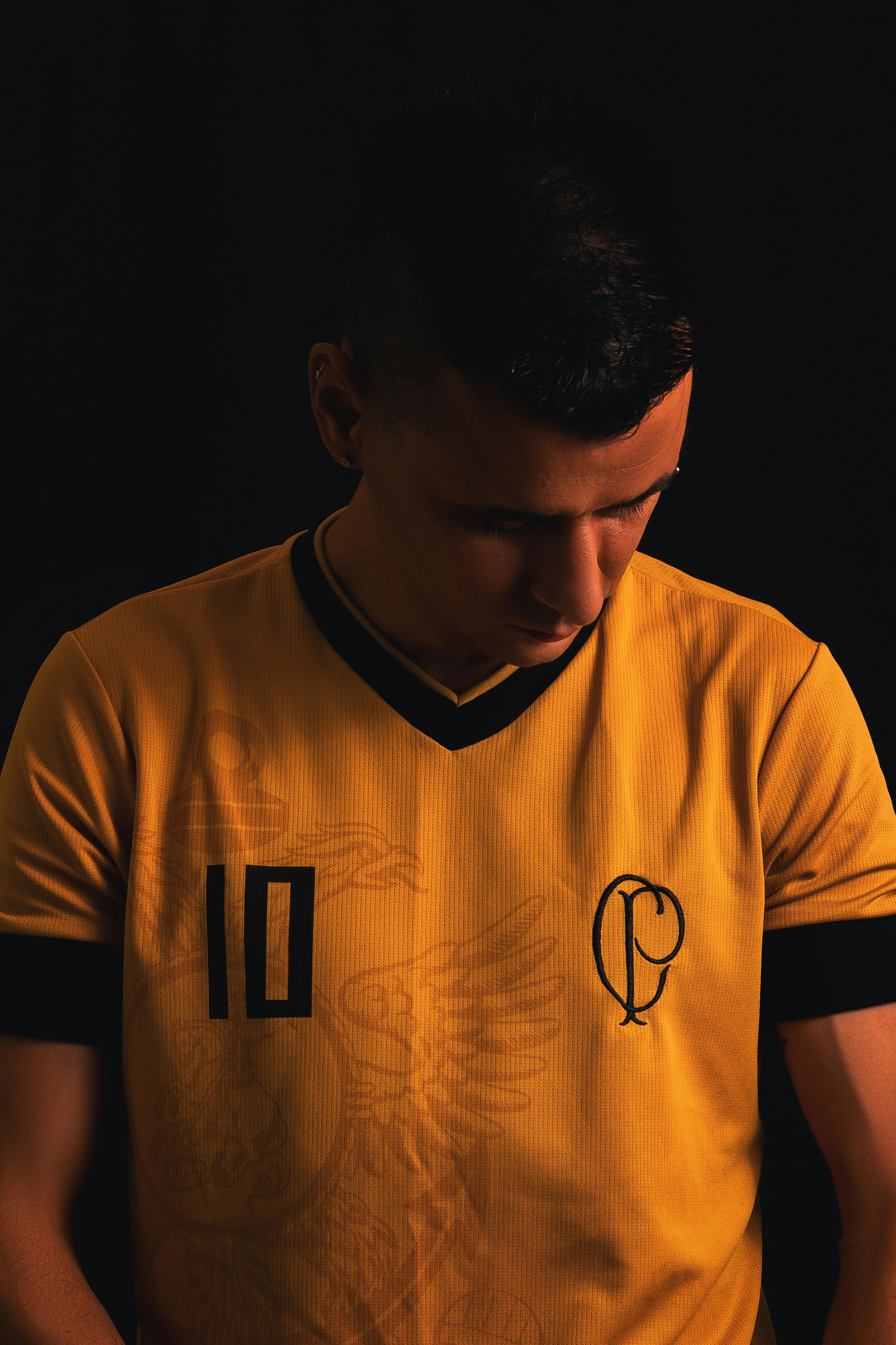 Free A young male posing in a yellow sports jersey with a CP logo in a moody setting. Stock Photo