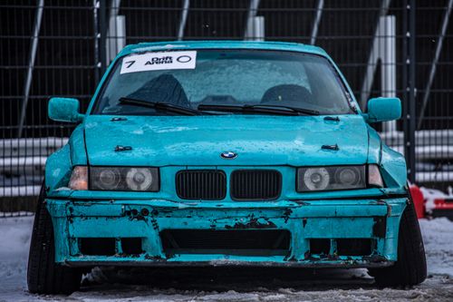 Free Close-up of a teal BMW drift car on a snow-covered track, emphasizing its rugged, sporty appeal. Stock Photo
