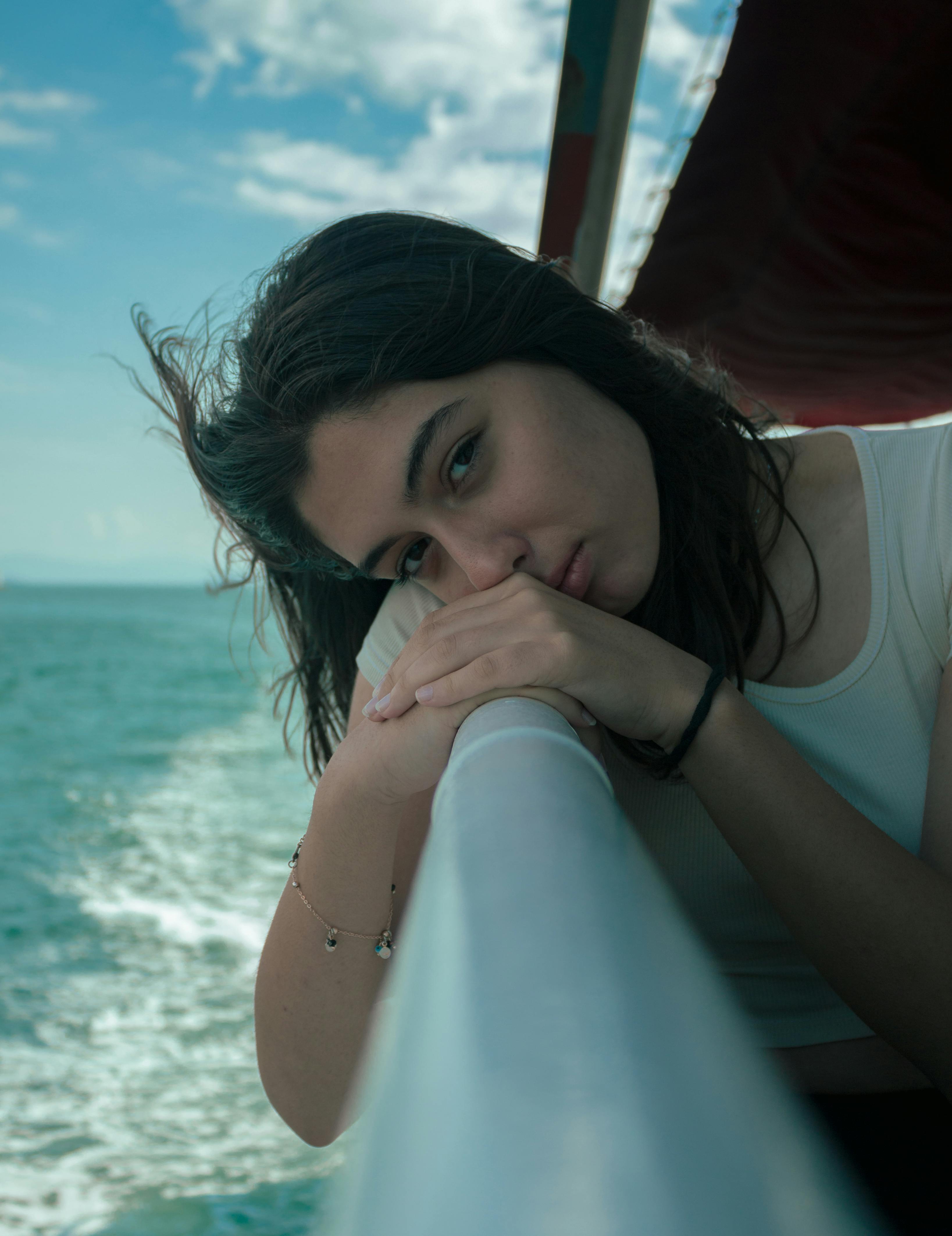 young woman on a boat resting her hand and head on the railing