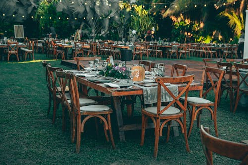 A wedding reception set up with wooden tables and chairs