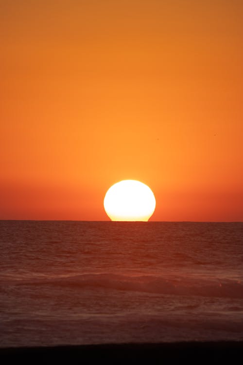A sunset over the ocean with the sun setting