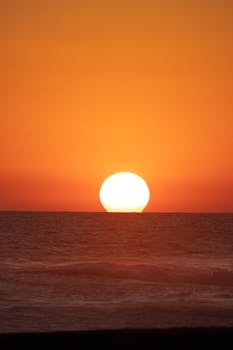A stunning sunset over the ocean horizon in Acapulco, Mexico, with vibrant orange skies.