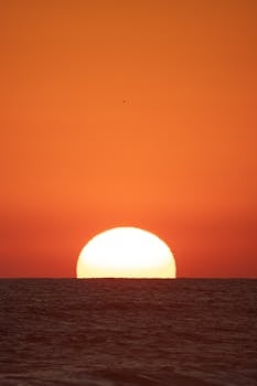 Captivating sunset view over the ocean in Acapulco, México, with a vibrant orange sky.