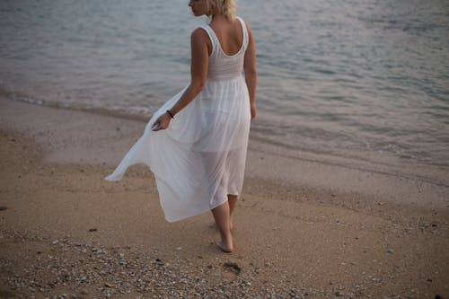 Woman in White Dress walking on Beach Shore