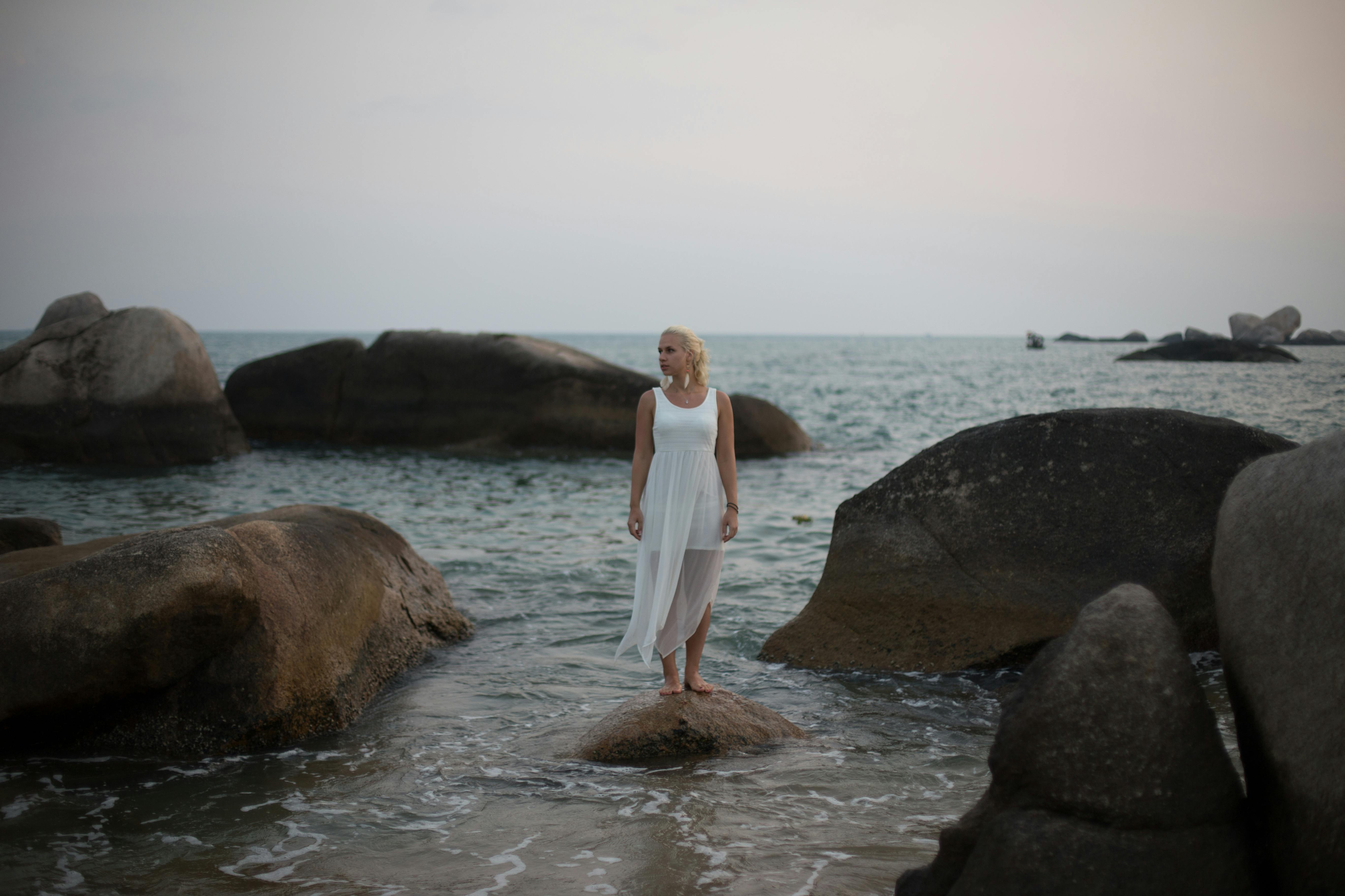 woman standing on a rock on the shore