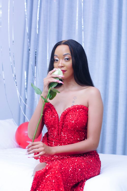 Free A stylish woman in a glistening red dress holds a white rose, captured elegantly in Gaborone, Botswana. Stock Photo