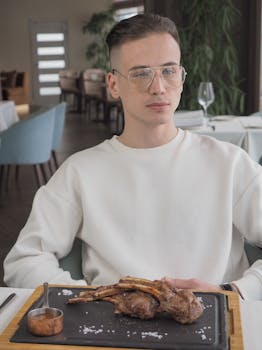 A young man enjoys a rib meal at a contemporary indoor restaurant setting.