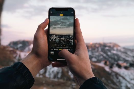 Man Photographing Mountains with Smartphone
