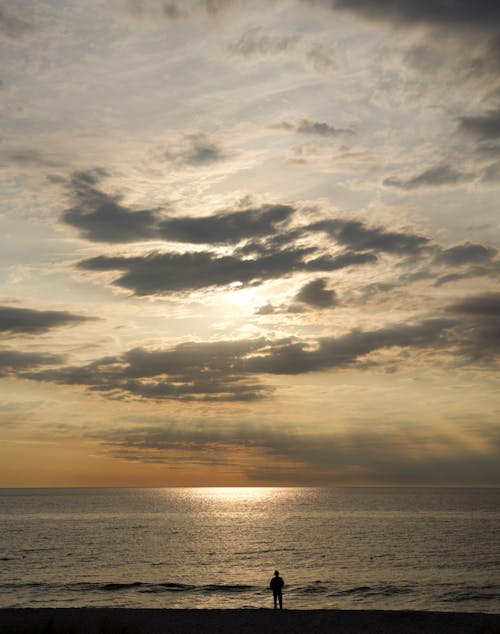 Sunlight behind Clouds over Sea Shore at Sunset