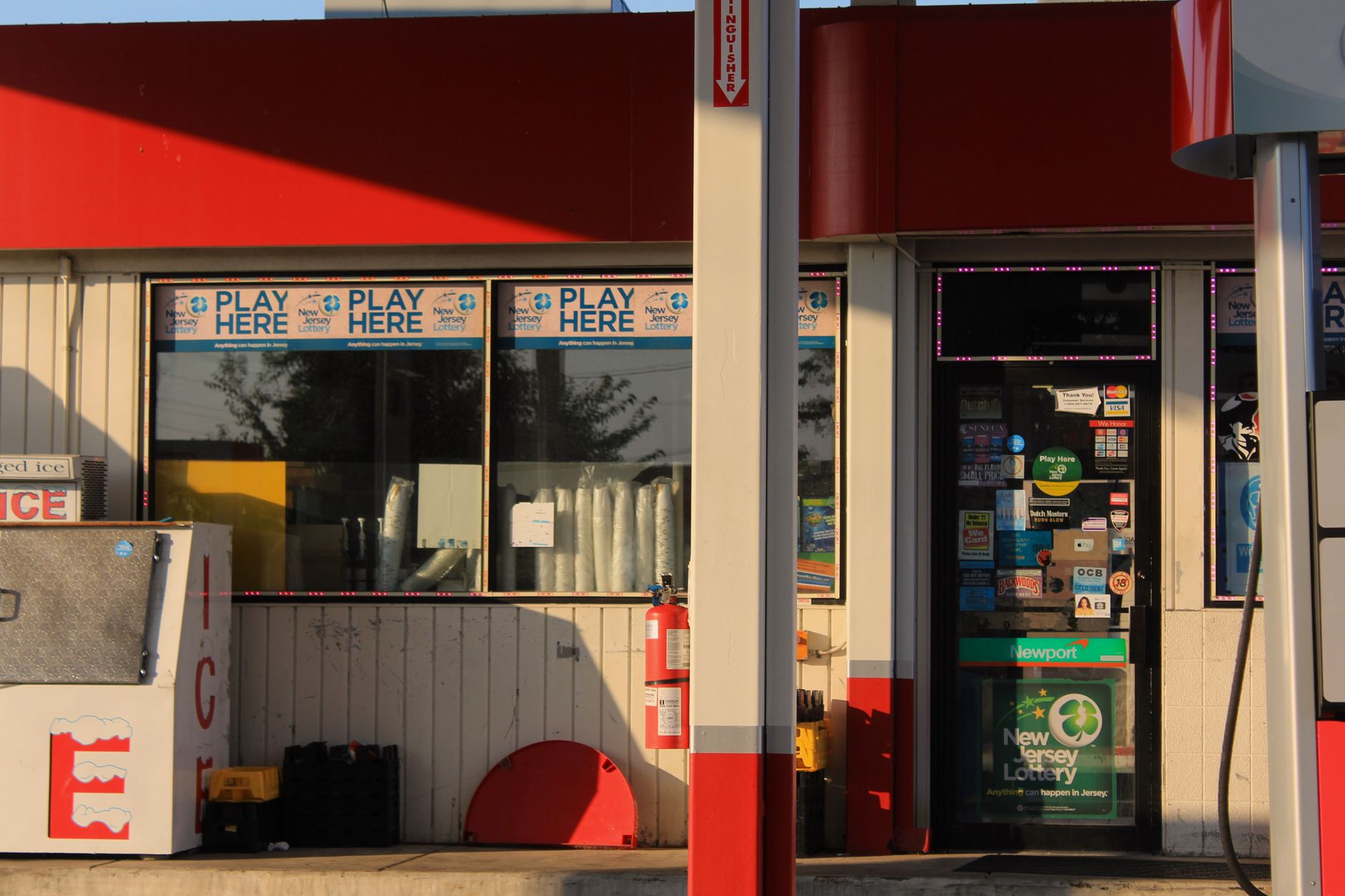 Convenience store entrance at a gas station featuring lottery signs in Bridgeton, New Jersey.