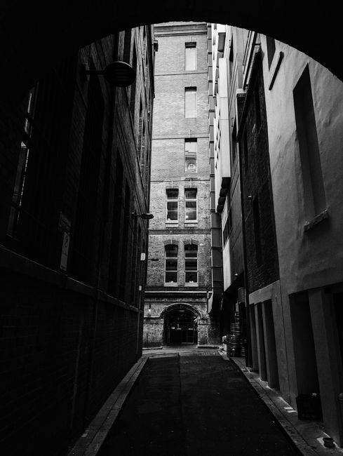 Moody black and white view of a narrow urban passage in Sydney, Australia.