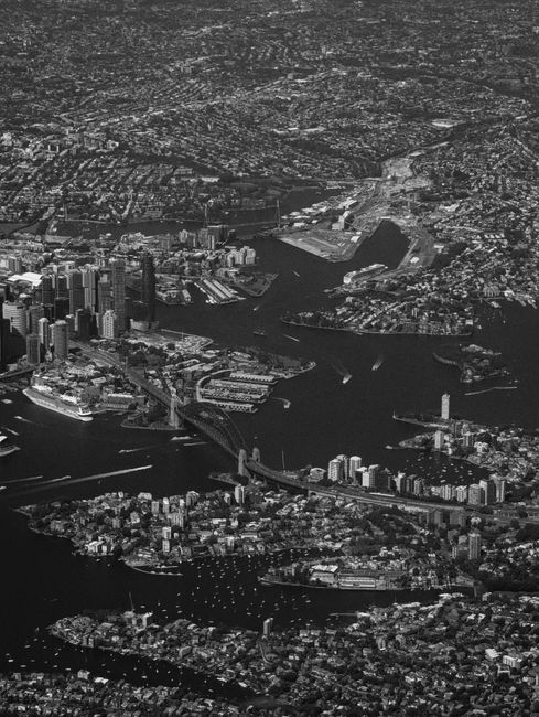 Black and white aerial view of Sydney Harbor with iconic cityscape details.