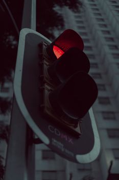 A low-angle view of a red traffic light against a city building in Mexico City.