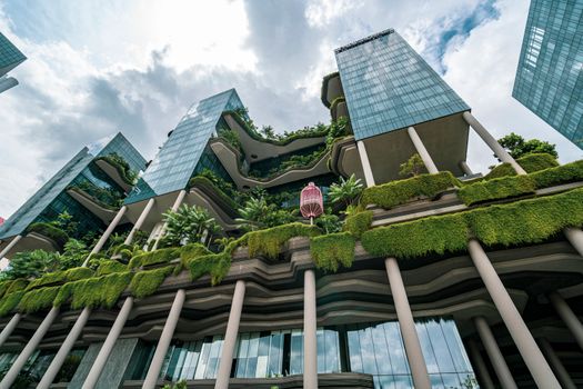 Innovative building with vertical gardens and glass facade showcasing eco-friendly architecture.