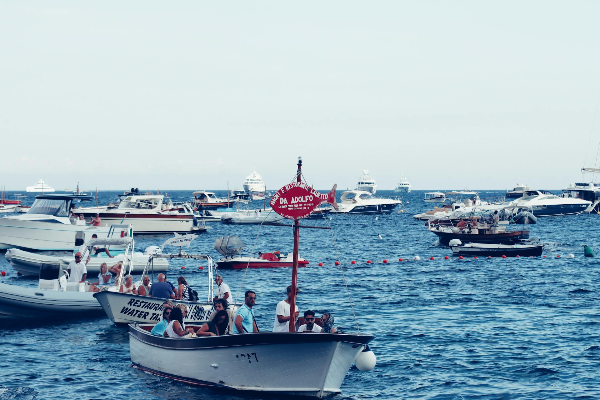 A lively bay scene with boats and people enjoying a sunny day on the water.