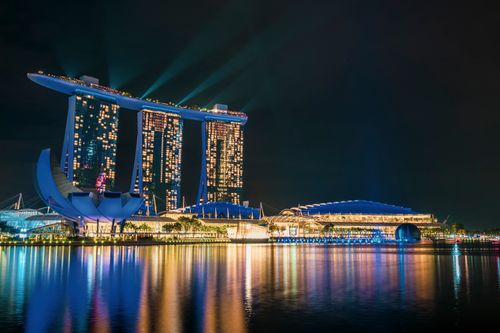 Free A stunning night view of the illuminated Marina Bay Sands and surrounding modern architecture reflecting on the water. Stock Photo
