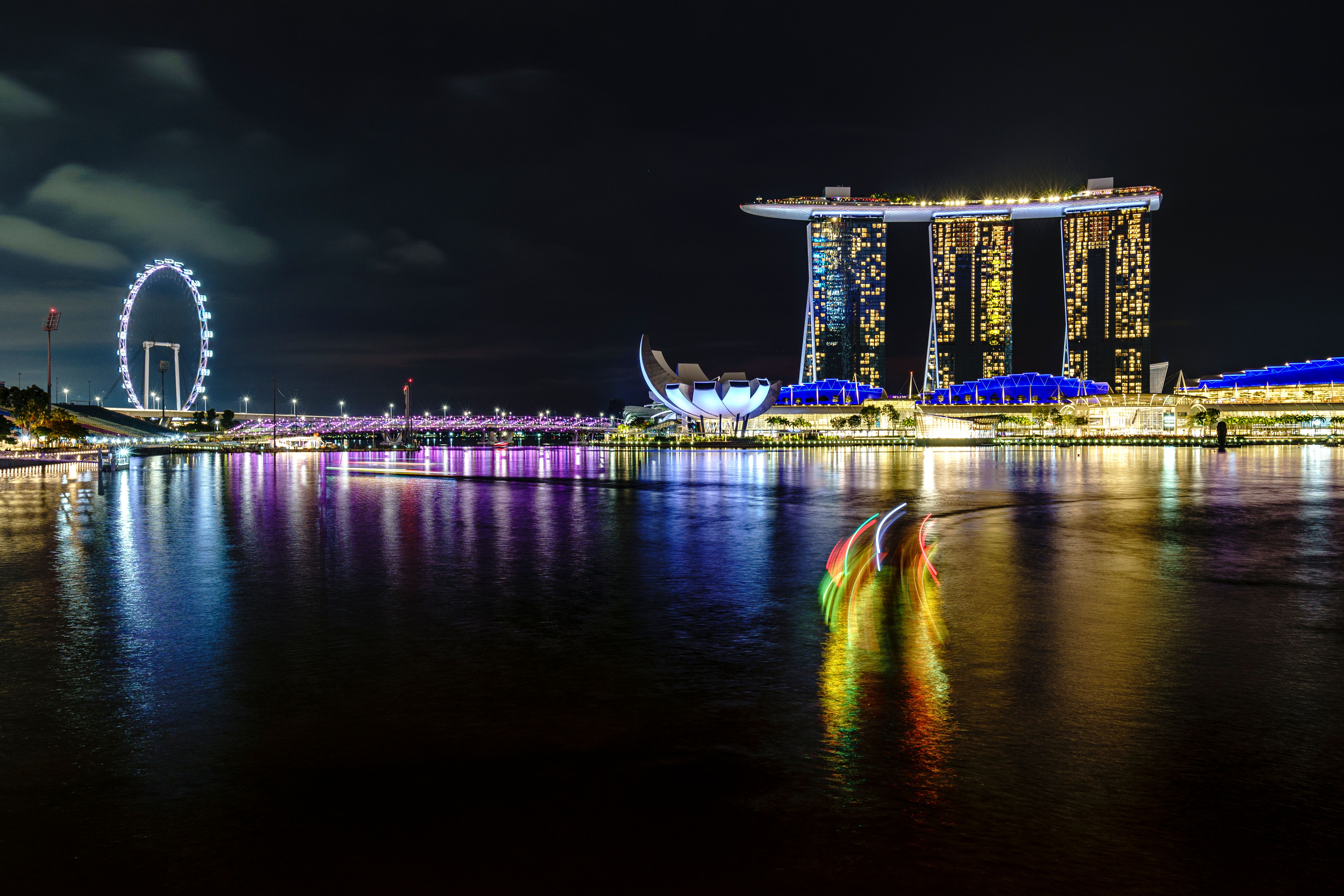 Marina Bay Sands hotel and the Singapore skyline illuminated at night, reflected on the calm waters of Marina Bay
