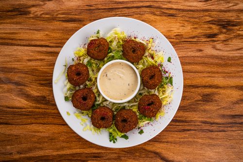 Free Top view of a falafel salad with creamy tahini on a wooden table. Stock Photo