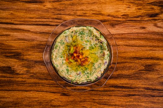 A delicious bowl of guacamole garnished with diced vegetables, served on a rustic wooden table.