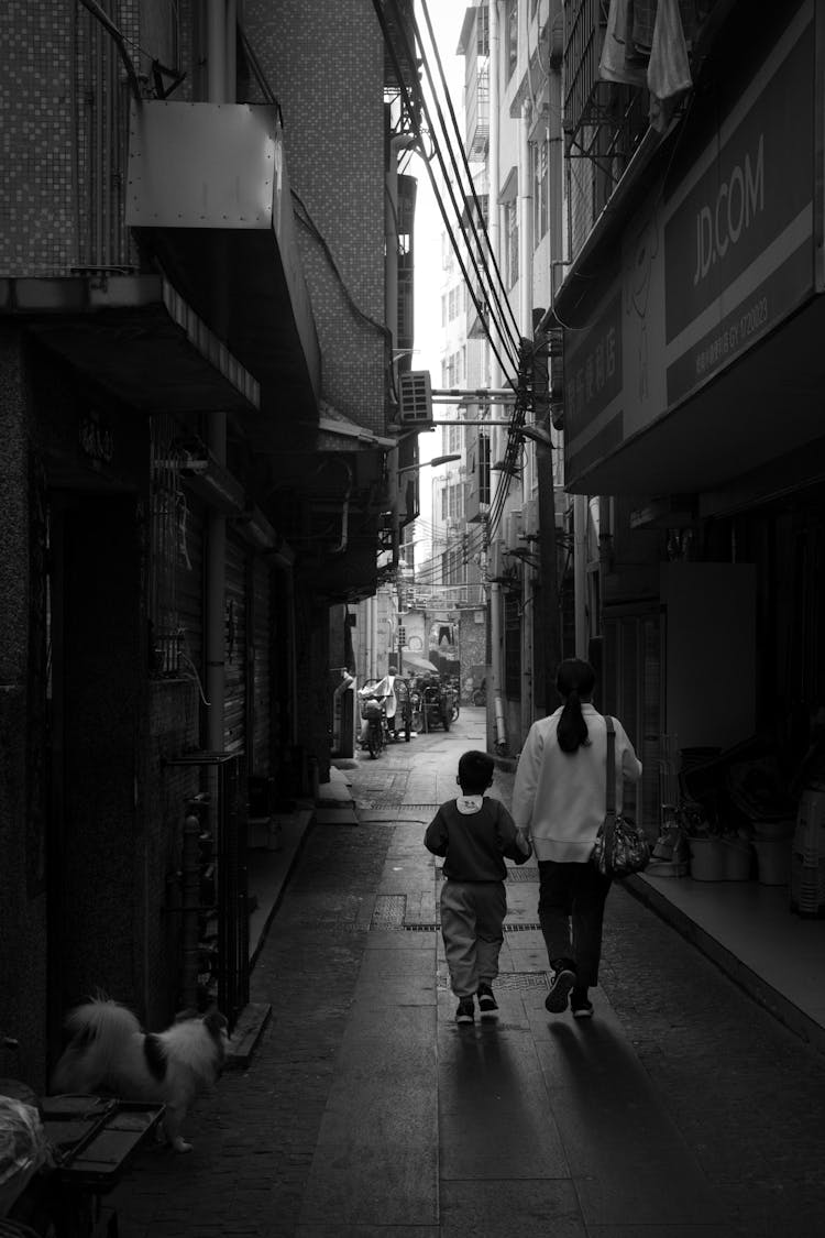 Woman And Child Walking On City Street