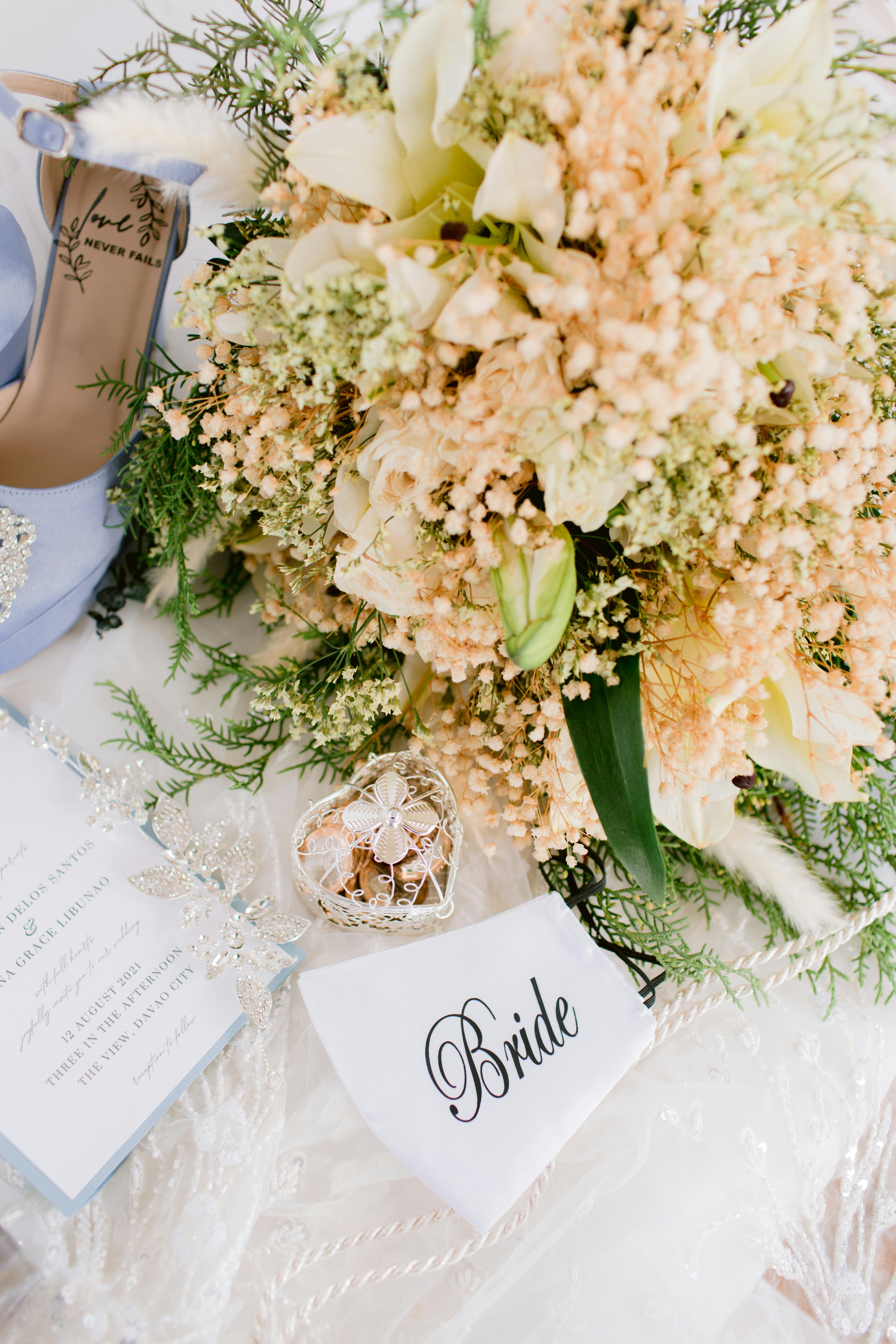 A beautifully arranged bridal setup with a floral bouquet, elegant shoes, and wedding accessories.