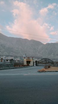 Scenic view of a small village with a gate at sunset, backed by a mountain range.