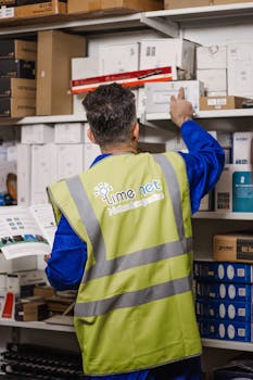 A warehouse worker in a reflective vest organizes inventory, showcasing efficient logistics in Erbil, Iraq.