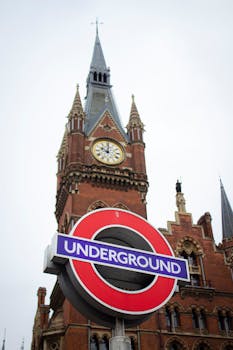 View of St Pancras Station clock tower behind the London Underground sign, symbolizing urban travel.