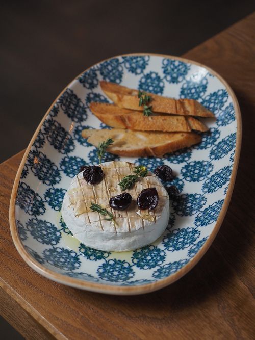 Free Baked camembert cheese topped with berries and served with toasted bread on a patterned plate. Stock Photo