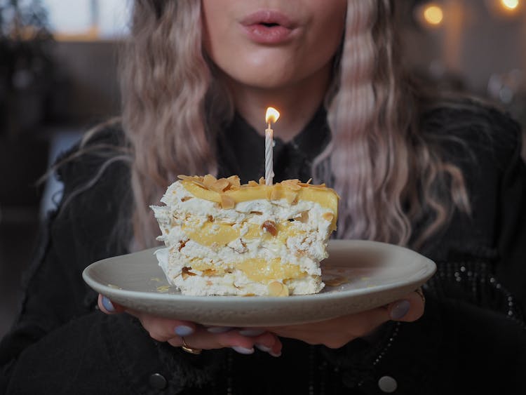 Photo Of A Woman Blowing Out A Candle From A Birthday Cake