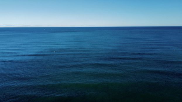 Tranquil aerial shot of the serene ocean horizon with clear blue skies in Valencia.